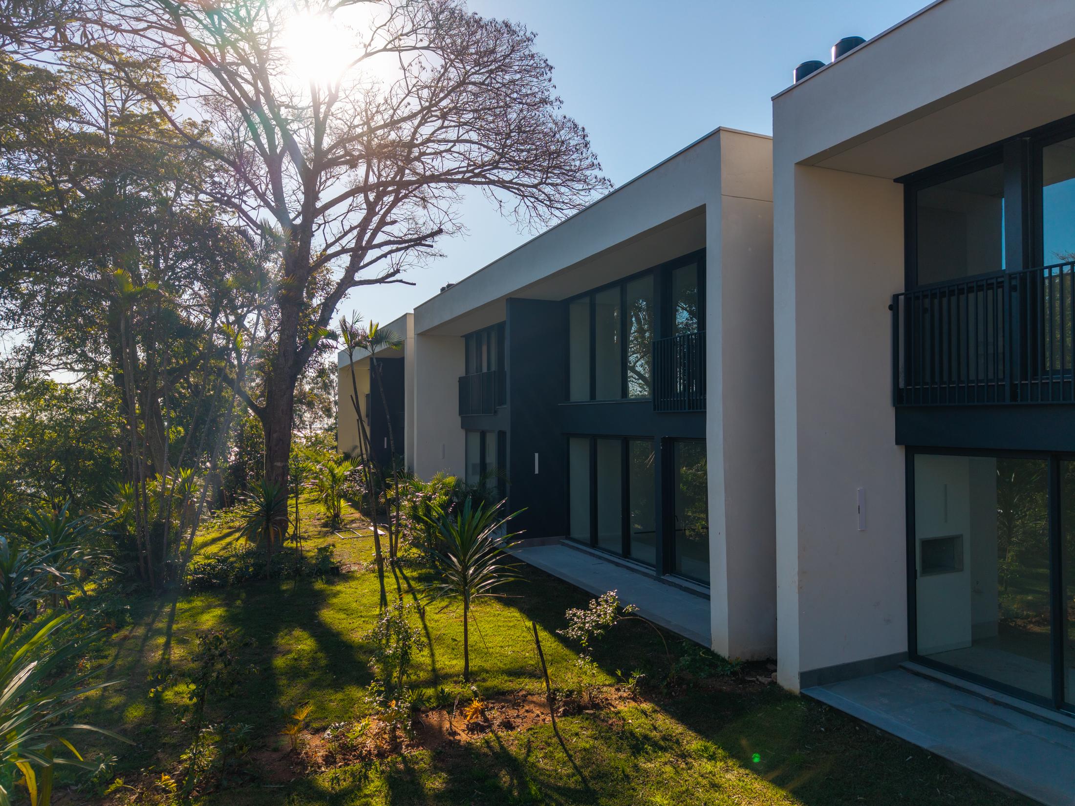 Casas do Aria com grandes janelas voltadas para o jardim e árvores